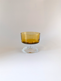 Amber glass dessert bowl on a clear stand against a white background