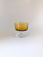 Amber glass dessert bowl on a clear stand against a white background