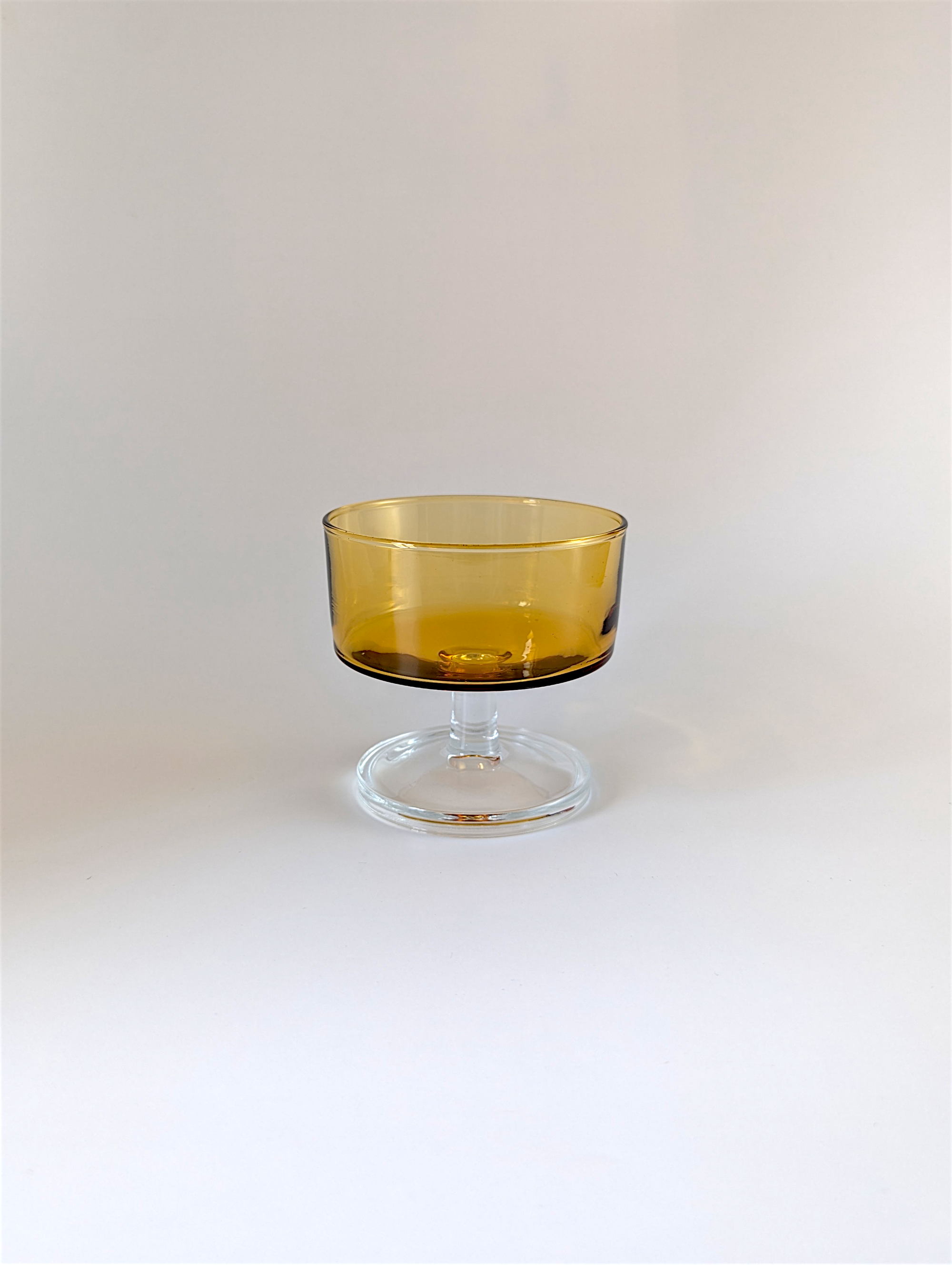 Amber glass dessert bowl on a clear stand against a white background