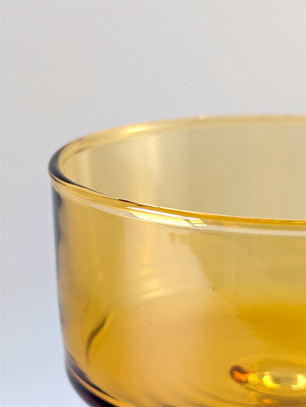 Close-up of a yellow glass bowl on a light gray background